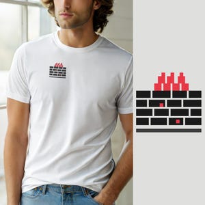 Può includere: Una t-shirt bianca a maniche corte con una piccola grafica sul petto sinistro. La grafica raffigura un muro di mattoni nero con fiamme rosse che si alzano dalla parte superiore e due piccoli quadrati rossi incastonati nel motivo.