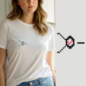 Puede incluir: Una camiseta blanca de manga corta con un pequeño gráfico de pixel art en el pecho. El diseño consiste en un círculo con borde negro y una marca de verificación roja en su interior, conectado a dos líneas diagonales de píxeles negros y un guion negro horizontal.