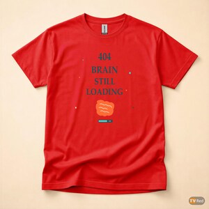 Op de afbeelding: Een rood t-shirt met de tekst "404 BRAIN STILL LOADING" in donkerblauw. Het ontwerp bevat een afbeelding van een hersen en een laadbalk. Het shirt is van het merk Gildan.