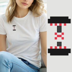 Peut inclure: Un t-shirt blanc à manches courtes avec un petit motif en pixel art sur la poitrine. Le design représente un haltère noir avec des accents rouges, rendu dans un style numérique en blocs. Le t-shirt possède un col rond et un tissu blanc uni.