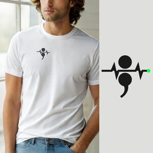 Könnte beinhalten: Ein weißes kurzärmeliges T-Shirt mit einer kleinen schwarzen Grafik auf der linken Brust. Das Design besteht aus einer horizontalen Herzschlaglinie, die einen schwarzen Kreis und ein Semikolon kreuzt und mit einem kleinen hellgrünen Punkt endet.