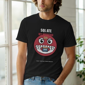 Może przedstawiać: Czarny t-shirt z czerwoną buzią i napisem "SQL ATE MY WEEKEND SQL" oraz "ONE QUERY TOO MANY". Grafika zawiera ikonę bazy danych. Koszulka jest noszona przez osobę. Projekt jest humorystyczny.