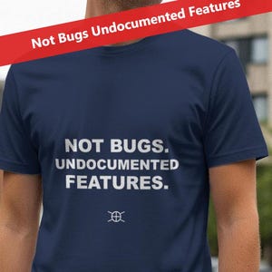 May include: A navy blue t-shirt with the text "NOT BUGS. UNDOCUMENTED FEATURES" in white. A small graphic is below the text. A red banner at the top reads "Not Bugs Undocumented Features."