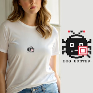 May include: A white short-sleeved t-shirt featuring a small, centered pixel art graphic of a black beetle with red accents on its antennae and a red square on its body. Below the graphic, the text BUG HUNTER is printed in a black pixelated font.