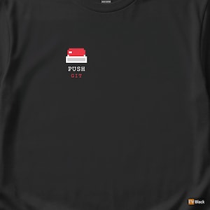 May include: Black t-shirt featuring a pixelated graphic of a red button with the words "PUSH GIT" in white and red font. The design is centered on the chest. The shirt is made of a heavy cotton material.