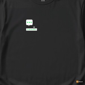 Peut inclure: T-shirt noir avec un motif blanc et vert. Le motif représente une bulle de dialogue avec trois points au-dessus d'une barre horizontale avec une flèche et des tirets verts. Le t-shirt est en coton épais.
