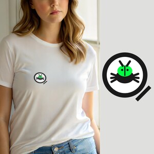 May include: A white short-sleeved t-shirt featuring a small graphic on the left chest. The graphic consists of a black circular outline containing a stylized green insect with black legs and antennae, positioned above a small black diagonal line.