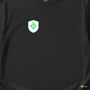 Peut inclure: T-shirt noir avec un écusson blanc orné d'un motif de cible vert. Le t-shirt est en coton épais. L'emblème est situé sur le côté supérieur gauche de la poitrine.
