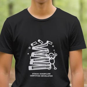 May include: Black t-shirt with a white graphic featuring a stack of rectangular shapes, a stick figure, and the text "STACK OVERFLOW CERTIFIED DEVELOPER". The shirt is a crew neck style.