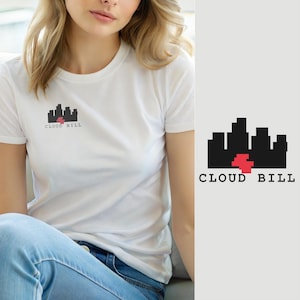 以下が含まれることがあります： 胸元に小さなグラフィックが施された白い半袖Tシャツ。グラフィックは、黒い街のスカイラインのシルエットに赤いピクセル状の形状が組み合わされたデザインで、黒い文字でCLOUD BILLと記されています。