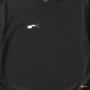 Op de afbeelding: Zwart t-shirt met een gepixelde afbeelding van een helikopter in wit en rood. Het ontwerp is gecentreerd op de borst. Het shirt is gemaakt van zwaar katoen.