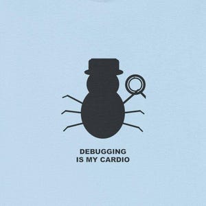 Könnte beinhalten: Hellblaues T-Shirt mit einer schwarzen Grafik einer Wanze mit Hut und Lupe. Der Text "DEBUGGING IS MY CARDIO" ist darunter aufgedruckt. Das T-Shirt ist aus einem weichen Material gefertigt.