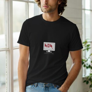 May include: Black crew neck t-shirt featuring a white computer screen graphic with the number "404" in red, and the word "DEBUGGING" below. The shirt is made of a soft material.