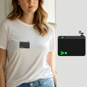 Puede incluir: Una camiseta blanca de manga corta con un pequeño gráfico en el pecho. El gráfico representa una ventana de terminal de computadora rectangular de color gris oscuro con un símbolo de comando verde y un punto verde, junto a pequeñas Z negras.