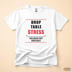 May include: White t-shirt with the text "DROP TABLE STRESS" in black and red, with the phrase "ROLLBACK NOT AVAILABLE" below. The shirt has a crew neck and short sleeves.