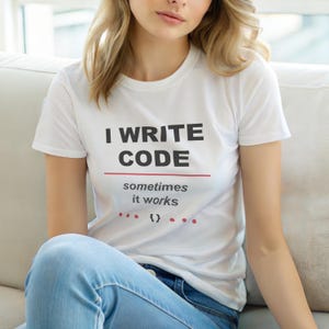 Könnte beinhalten: Weißes T-Shirt mit dem schwarzen Text "I WRITE CODE", darunter "sometimes it works" in kleinerer Schrift. Das Shirt hat auch rote Punkte und geschweifte Klammern. Die Person trägt eine blaue Jeans.