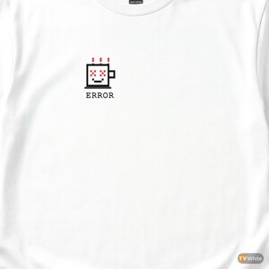 May include: White t-shirt featuring a pixelated coffee cup design with the word "ERROR" below it. The cup has red accents and a black outline. The shirt is made of a heavy cotton material.