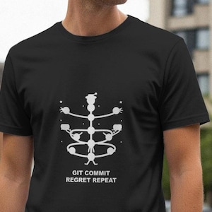 May include: Black t-shirt with a white graphic design and the text "GIT COMMIT REGRET REPEAT". The graphic is a stylized, abstract representation of a figure. The shirt is made of a soft material.