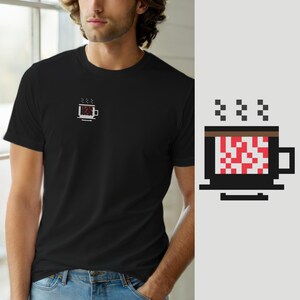 以下が含まれることがあります： 左胸に小さなピクセルアートのグラフィックが施された黒の半袖Tシャツ。グラフィックは、茶色の縁取り、本体の赤と白の市松模様、そしてその上に3つの小さな黒い蒸気の雲が描かれたコーヒーマグカップを表しています。