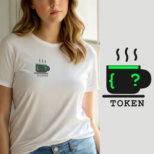 May include: A white short-sleeve t-shirt featuring a small graphic on the chest. The graphic depicts a dark gray coffee mug with a bright green rim, a green curly bracket, and a green question mark. Below the mug is the word TOKEN in black.