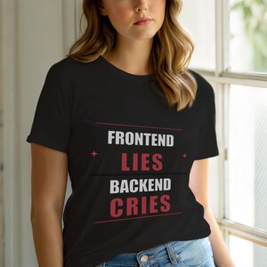 Op de afbeelding: Zwart T-shirt met de tekst "FRONTEND LIES BACKEND CRIES" in wit en rood. Het shirt heeft een ronde hals en korte mouwen. De tekst staat in het midden van de voorkant van het shirt.