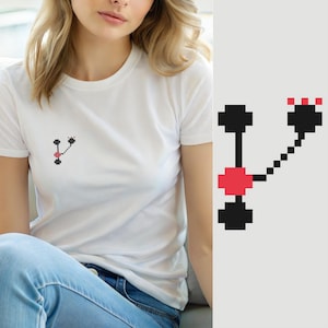 Puede incluir: Una camiseta blanca de manga corta con un pequeño gráfico de pixel art en el pecho izquierdo. El diseño consiste en píxeles cuadrados negros y rojos dispuestos en una estructura ramificada con un nodo central rojo y tres grupos negros.