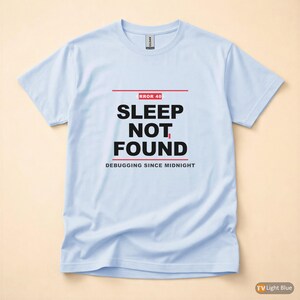 Peut inclure: T-shirt bleu clair avec l'inscription "ERROR 40 SLEEP NOT FOUND DEBUGGING SINCE MIDNIGHT" en noir et rouge. Le t-shirt est à col rond et à manches courtes.