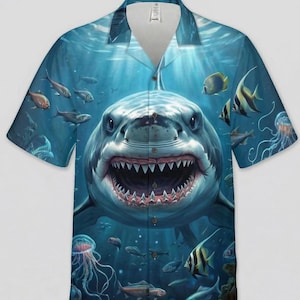 May include: Short-sleeved button-down shirt featuring a vibrant underwater scene. The design showcases a large shark with an open mouth, surrounded by various fish and jellyfish in shades of blue and green.