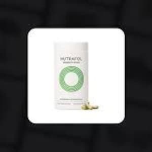 May include: White cylindrical container of Nutrafol supplements with a green circular design and text. A few capsules are scattered near the base of the container. The background is a soft white square against a dark background.