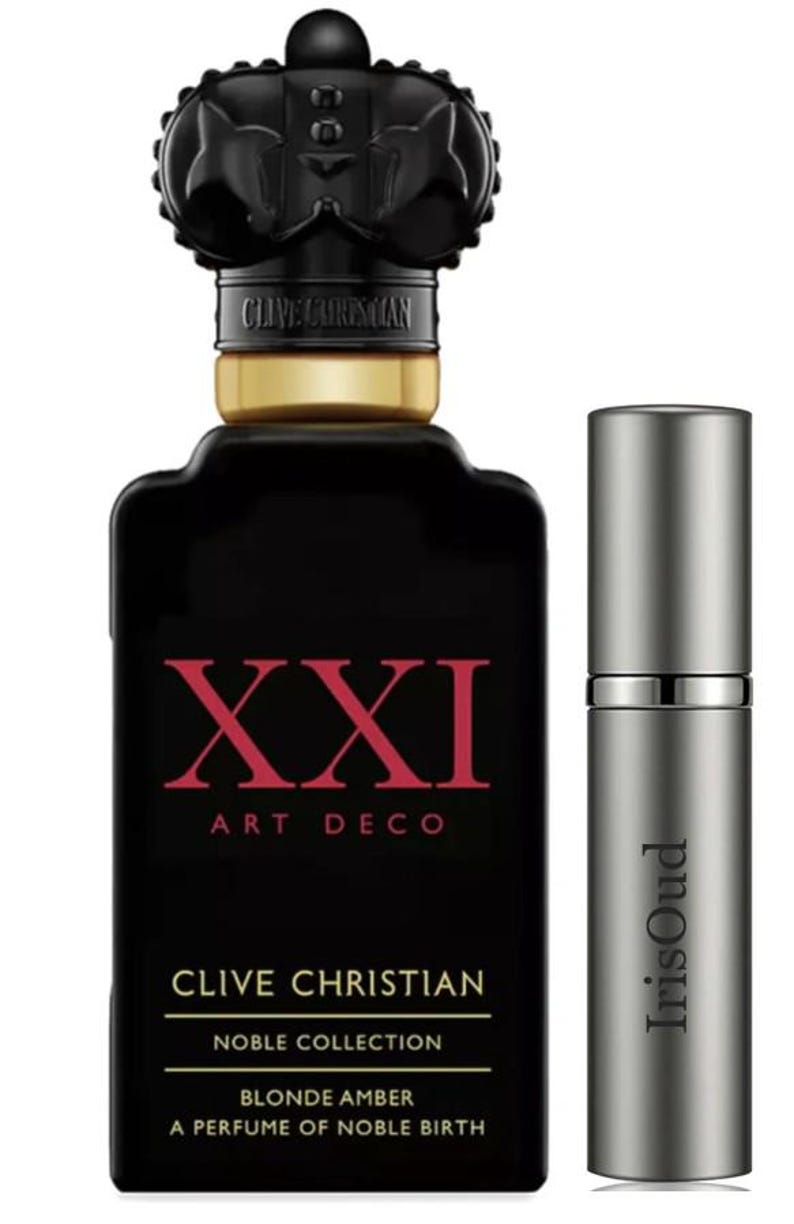 Puede incluir: Frasco de perfume negro con tap&oacute;n en forma de corona y el texto "XXI ART DECO" en rojo. El frasco est&aacute; etiquetado como "CLIVE CHRISTIAN" y "NOBLE COLLECTION". Junto a &eacute;l, un frasco de spray de viaje plateado con "IrisOud".