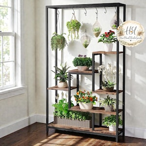 Puede incluir: Un estante para plantas de metal negro y madera con múltiples estantes y ganchos para colgar. El estante exhibe varias plantas en macetas, incluyendo plantas colgantes, orquídeas y plantas con flores. Los estantes son de madera con un acabado rústico.