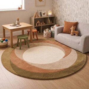 Könnte beinhalten: Ein runder Teppich mit einem Spiralmuster in Grün-, Braun- und Beigetönen. Der Teppich liegt auf einem Holzboden, und der Raum umfasst einen kleinen Tisch, Hocker, ein Sofa und ein Bücherregal, wodurch ein gemütlicher Kinderspielbereich entsteht.