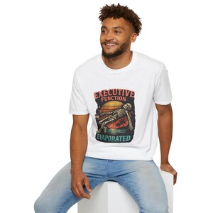 May include: White t-shirt with a graphic of a skeleton on a beach at sunset. The text "EXECUTIVE FUNCTION EVAPORATED" is above and below the image. The shirt is worn by a person.