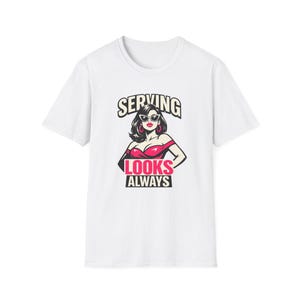 Può includere: T-shirt bianca con un'illustrazione retrò di una donna con occhiali da sole e un vestito rosso. Il testo sopra l'illustrazione recita "SERVING", e sotto, "LOOKS ALWAYS". Il design ha uno stile vintage, fumettistico.