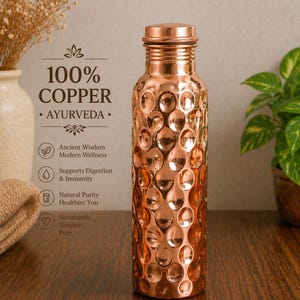 Puede incluir: Una botella de agua de cobre con una superficie texturizada y con hoyuelos. La botella lleva la etiqueta "100% COBRE" y "AYURVEDA". La imagen también incluye texto sobre la sabiduría antigua, la digestión, la inmunidad y la pureza natural.