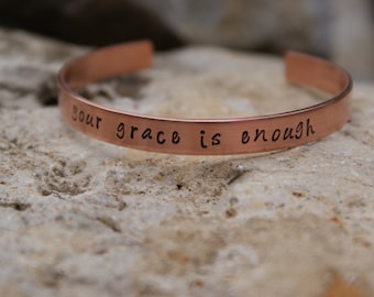 May include: A copper bracelet with the inscription "Your grace is enough".