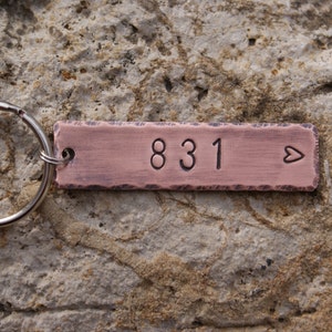 May include: A copper keychain with the number 831 and a small heart engraved on it.