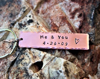 May include: A copper keychain with a hammered finish and a personalized inscription that reads "Me & You 4.26.09" with a small heart symbol.