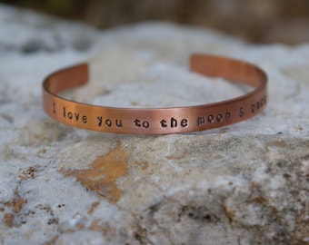 May include: A copper bracelet with the inscription "I love you to the moon & back".