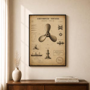 May include: A framed vintage-style technical drawing print titled SCHIFFSPROPELLER - SYSTEM RESSEL. The beige paper features a large three-bladed ship propeller illustration, smaller mechanical diagrams, a ship silhouette, and technical text.