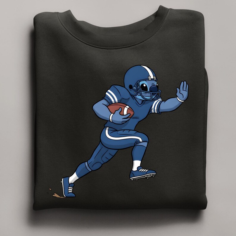 May include: Black sweatshirt with a cartoon character in a blue American football uniform, helmet, and holding a football. The character is running with one arm raised. The design includes white stripes and accents.