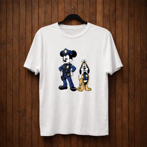 May include: White t-shirt featuring a cartoon illustration of Mickey Mouse and Pluto dressed as police officers. Mickey Mouse is in a blue uniform with a police hat, and Pluto is in a yellow uniform. The design is centered on the shirt.