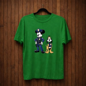 May include: Green t-shirt featuring a cartoon illustration of Mickey Mouse and Pluto dressed as police officers. Mickey Mouse is in a blue uniform with a police hat, and Pluto is in a yellow uniform.