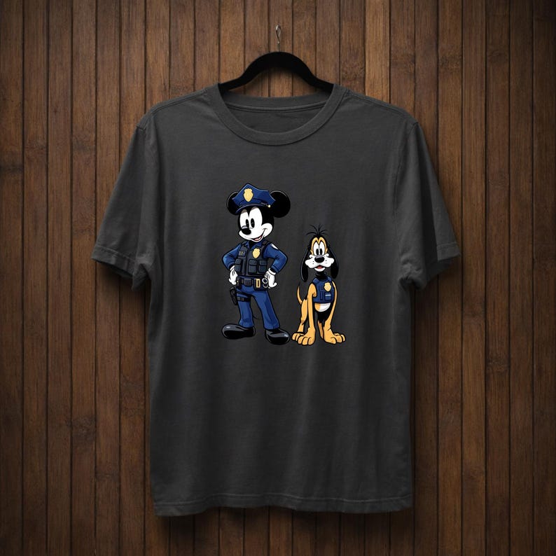 May include: Dark gray t-shirt featuring a cartoon illustration of Mickey Mouse and Pluto dressed as police officers. Mickey Mouse is in a blue police uniform with a hat, and Pluto is wearing a police vest. The design is centered on the shirt.