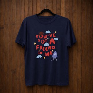 Op de afbeelding: Een witte keramische mok met een zwarte handgreep en de tekst "But First, Coffee" in een vetgedrukte, zwarte letter. De mok staat tegen een vage achtergrond, wat een gezellige setting suggereert.