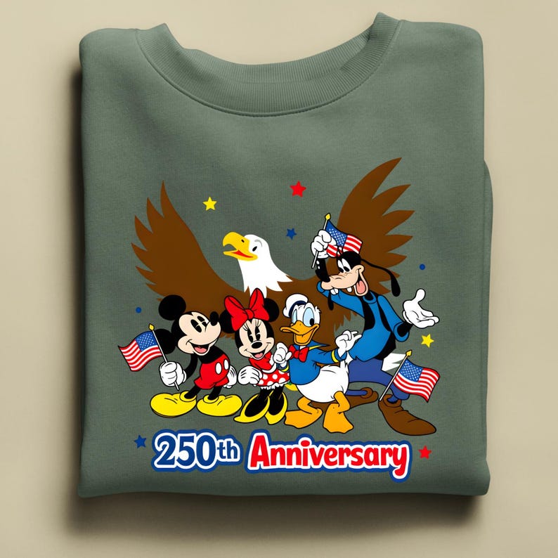 Puede incluir: Una sudadera verde salvia con Mickey Mouse, Minnie Mouse, Donald Duck y Goofy con banderas americanas y un &aacute;guila calva. El texto "250th Anniversary" est&aacute; en rojo y azul.