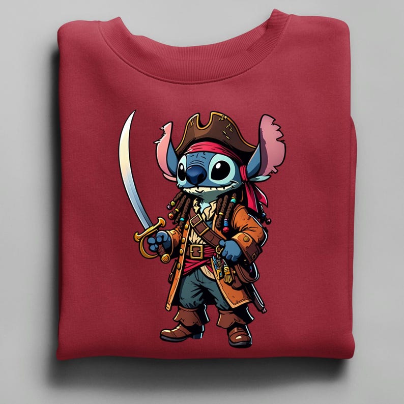 May include: A maroon sweatshirt featuring a cartoon pirate character. The character is blue with large eyes, wearing a brown pirate hat, coat, and holding a sword. The design is centered on the folded sweatshirt.