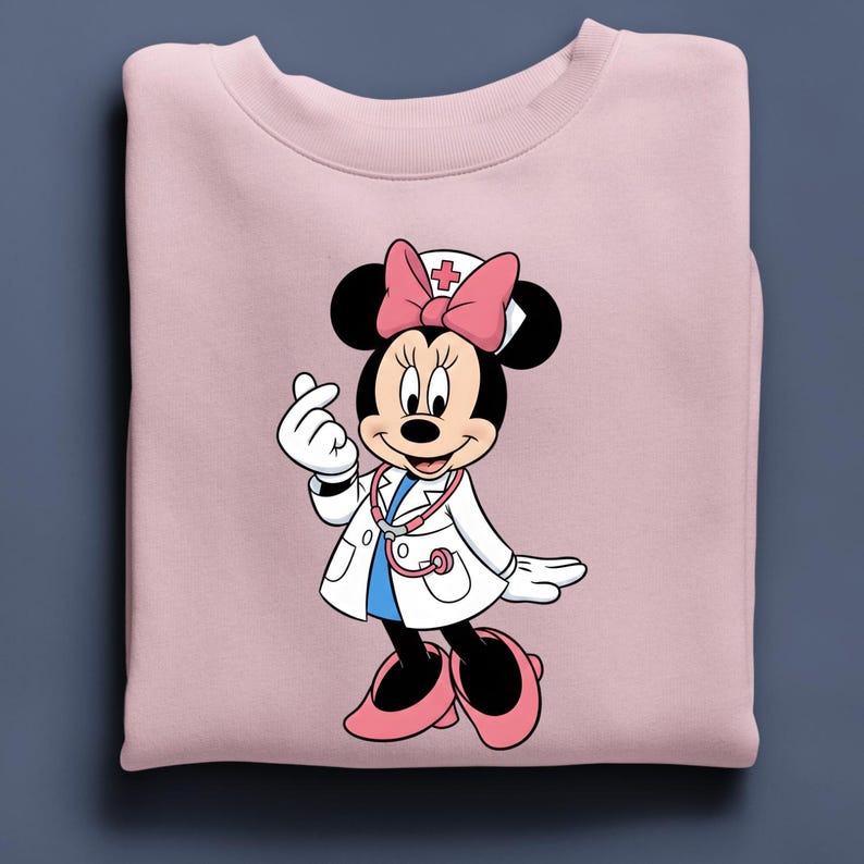 Puede incluir: Sudadera rosa claro con un dibujo de Minnie Mouse vestida de enfermera. Minnie Mouse lleva una bata blanca, un lazo rosa y un estetoscopio. El dibujo est&aacute; centrado en la sudadera.