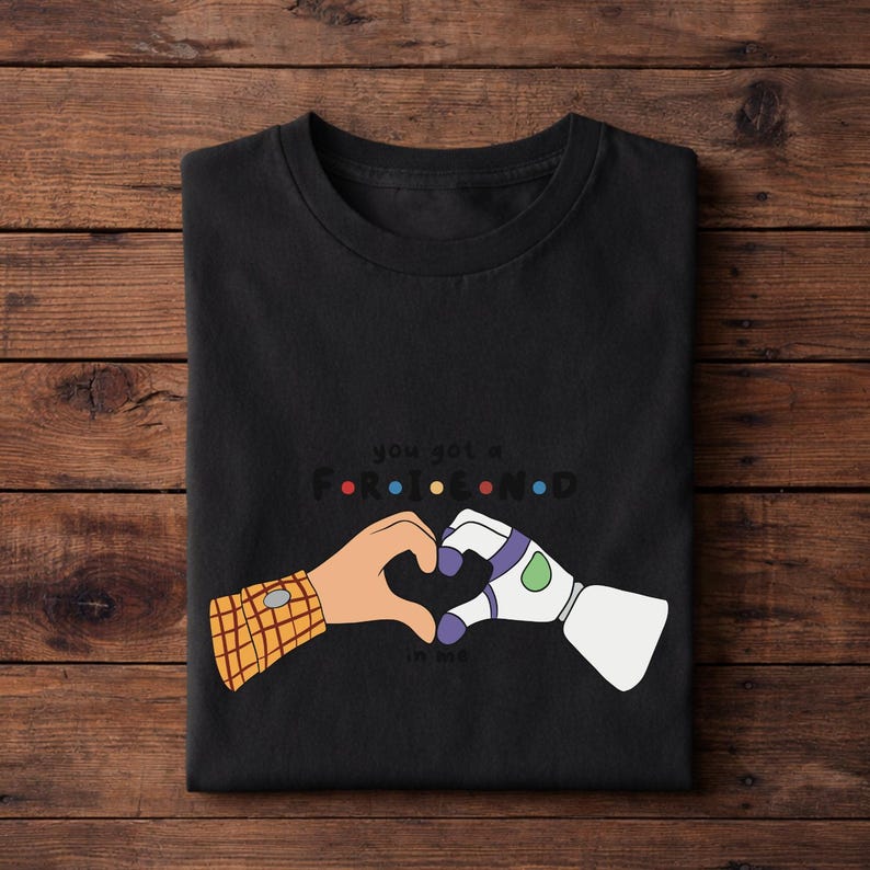 May include: Black t-shirt featuring a heart made of cartoon hands, one with a plaid sleeve and the other a white and purple robotic hand. The text "you got a friend in me" is above the hands.