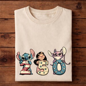 Puede incluir: Camiseta color crema con los personajes Stitch, Lilo y Angel sosteniendo los n&uacute;meros 2, 5 y 0. Los n&uacute;meros est&aacute;n decorados con estrellas rojas, blancas y azules, y los personajes son de estilo caricatura.
